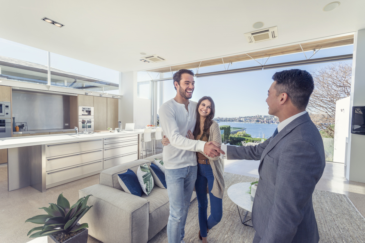 real estate agent shaking hands with couple in luxury home